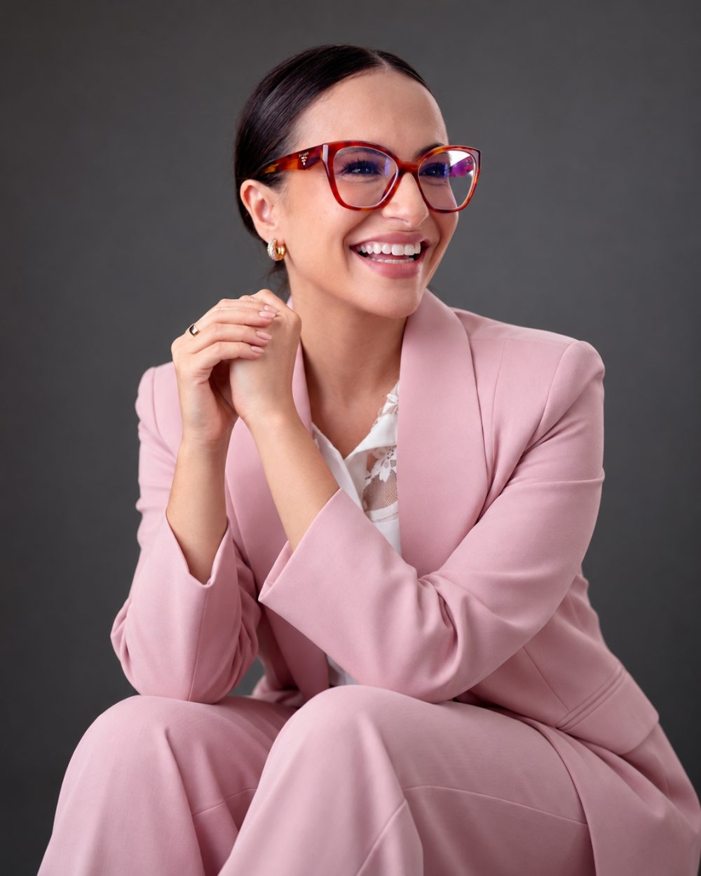 Dra. Nathália Chinellato sentada, de terno rosa, sorrindo